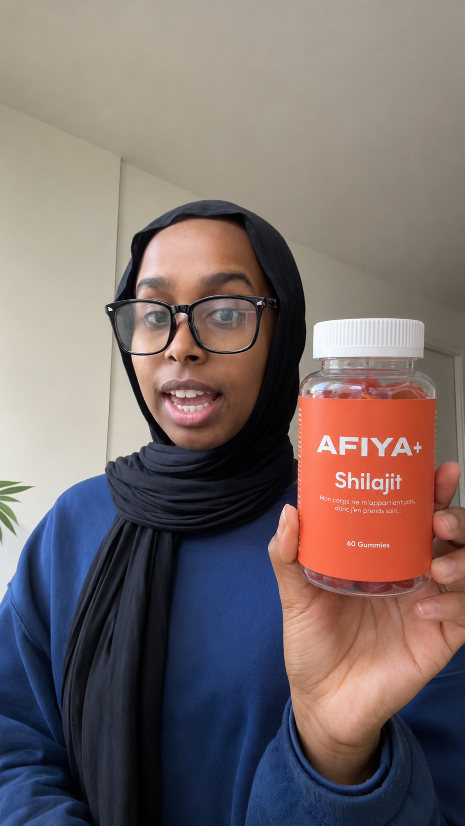 Cliente avec lunettes présentant un flacon Afiya+ Shilajit à la caméra